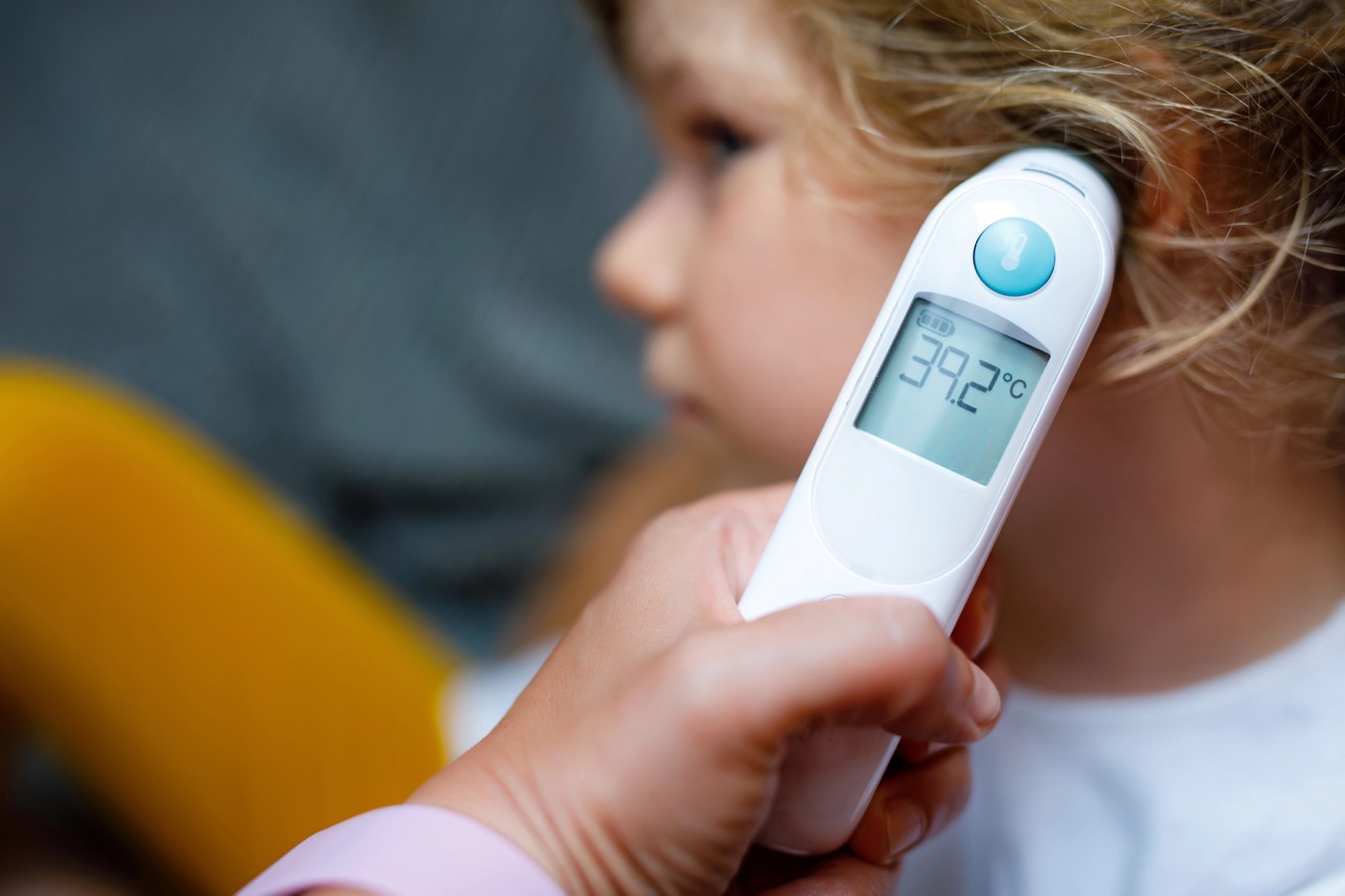 Mother takes temperature for her little preschool daughter, sick child with infrared in ear thermometer at home, high grade fever Mother hand holding digital infrared thermometer. Mother takes temperature for her little preschool daughter, sick child with infrared in ear thermometer at home, high grade fever Mother hand holding digital infrared thermometer.